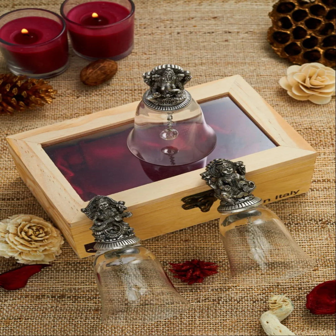 Decorative glass bottles with metal lids in a wooden box on a textured surface with candles and flowers.