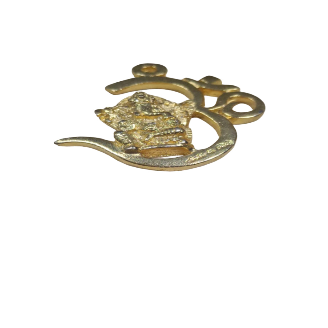 Gold pendant with intricate design on a wooden surface